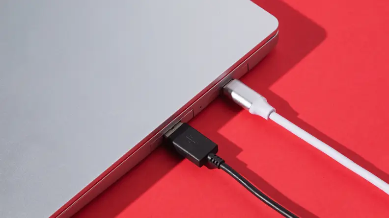 Close-up of the side ports of the laptop with two cables plugged in.