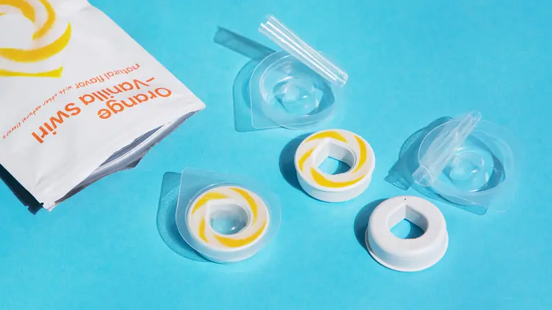 Several pods and plastic packaging laid out on blue background