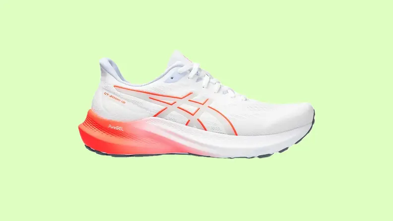 An orange and white sneaker against a green background.