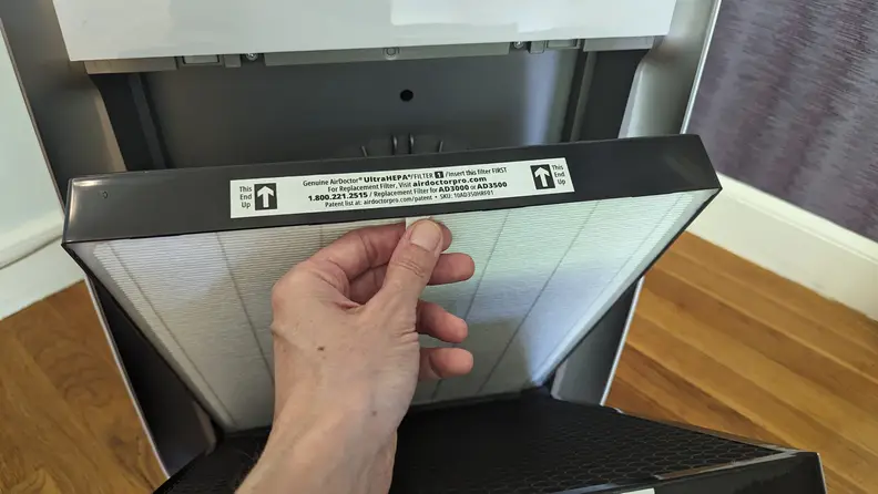 A hand holds the tab on the front of the Air Doctor Pro 3500i’s UltraHEPA filter, which demonstrated some of the best air purifier performance we’ve seen.