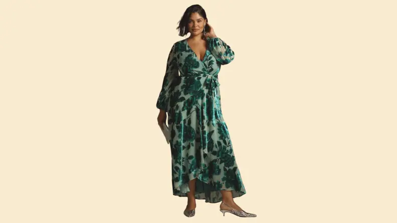 A model wearing a green dress with a floral velvet motif.