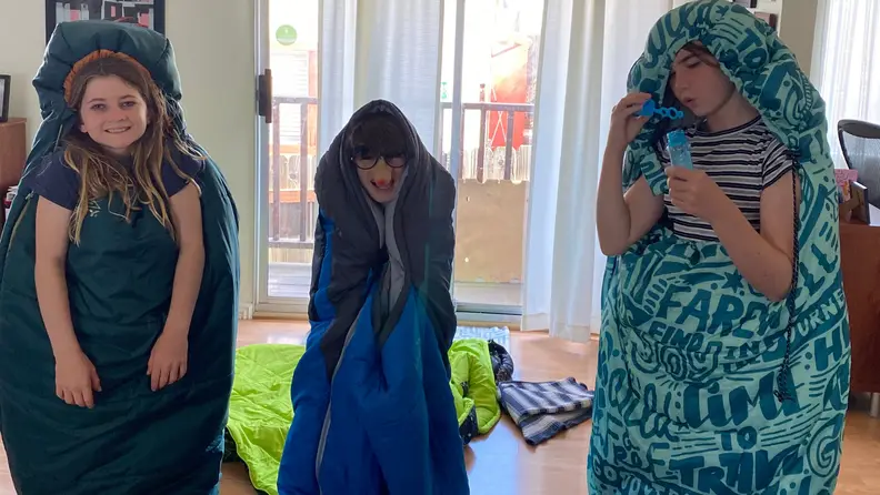 Three kids sanding in bags looking goofy.