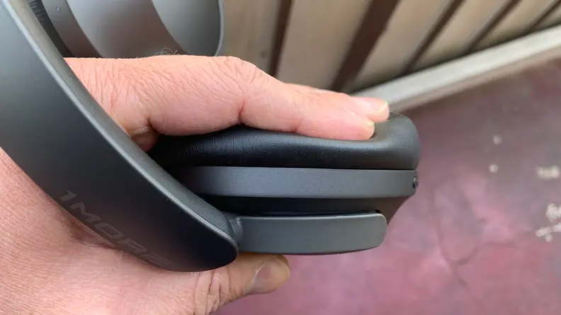 A hand pressing on the headphones' ear pads.