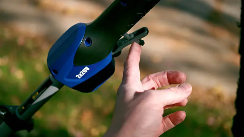 A finger pushes a trigger on a tool