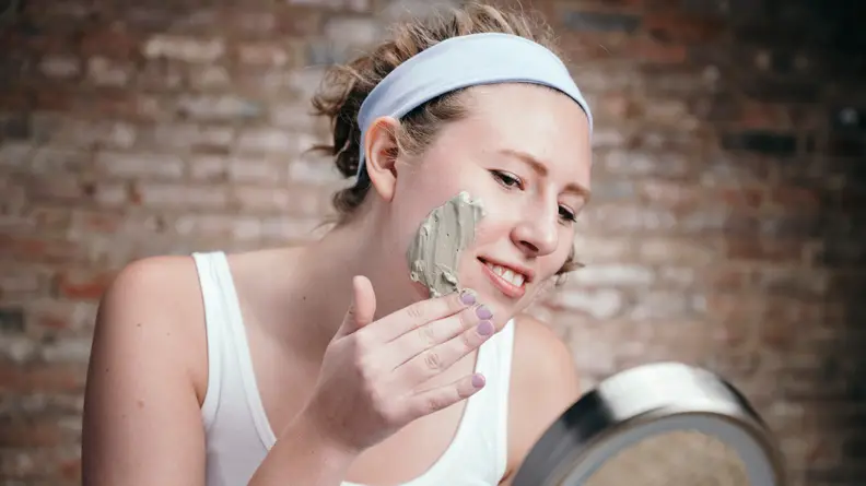 A photo of a woman applying a face mask.