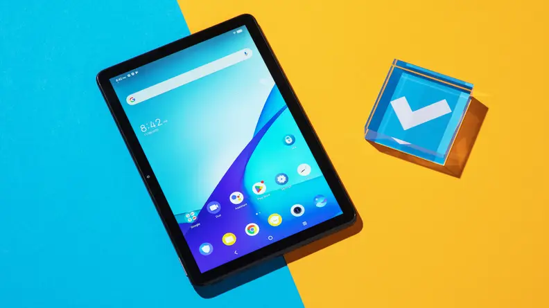 TCL Tab 10s tablet sitting next to blue acrylic paperweight with a white checkmark in the middle.