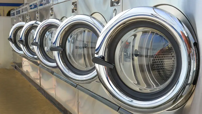 A series of open laundromat washer doors.