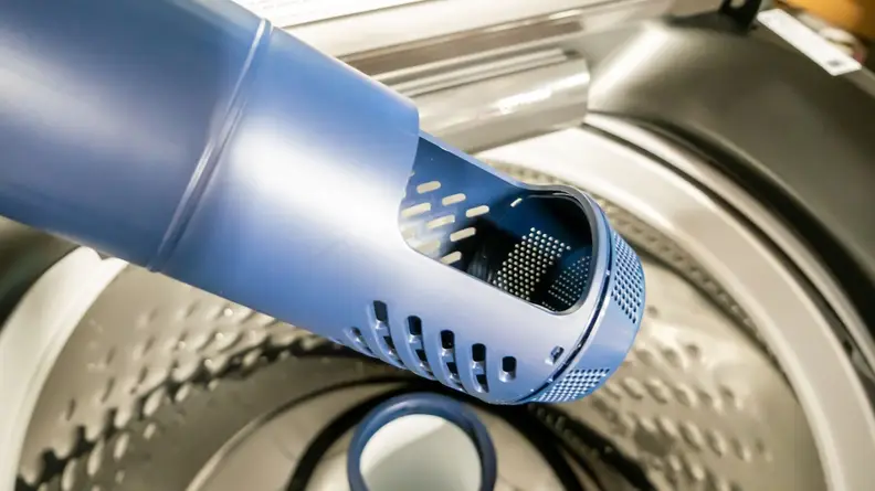 Blue, plastic pole agitator with pet hair filter inside of the Maytag MVW6500MBK top-loading washer.
