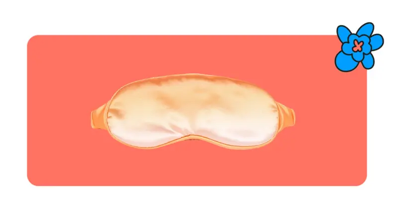 Product shot of a orange satin Loftie sleep mask in front of a red background with a blue cartoon flower.