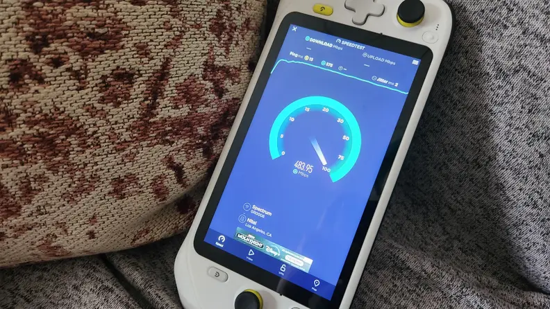 A handheld gaming console showing internet download speed on its screen
