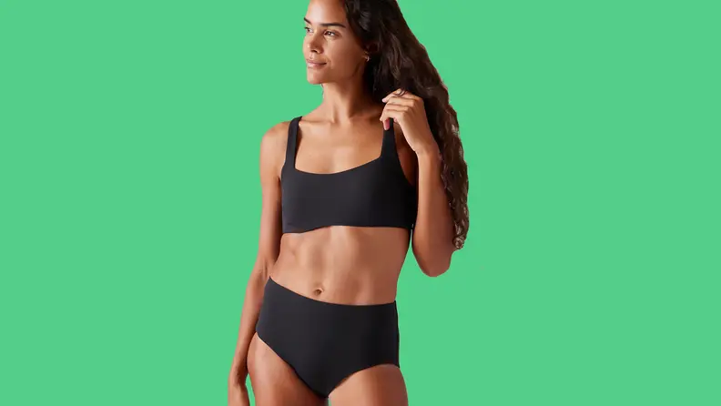 Tan woman wearing black bikini top on green background