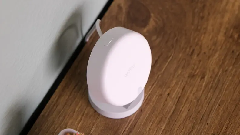 The Aqara FP2 presence sensor sits on its stand on a wooden desk