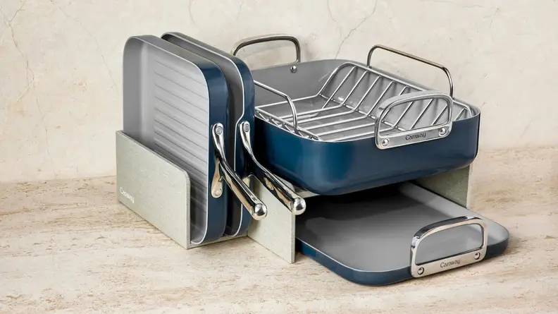 Navy blue ceramic skillets and pans arranged together inside of magnetic storage holder on top of countertop surface.