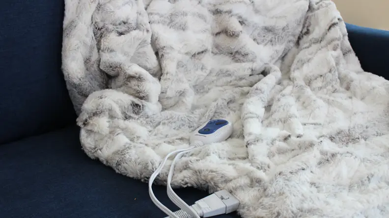 The BeautyRest electric blanket thrown over a blue couch.