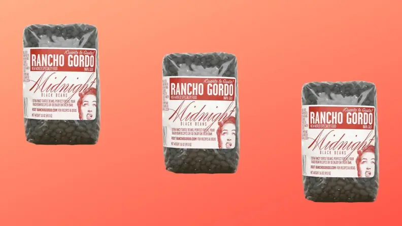 Three packages of black beans arranged in a diagonal row on a red background.