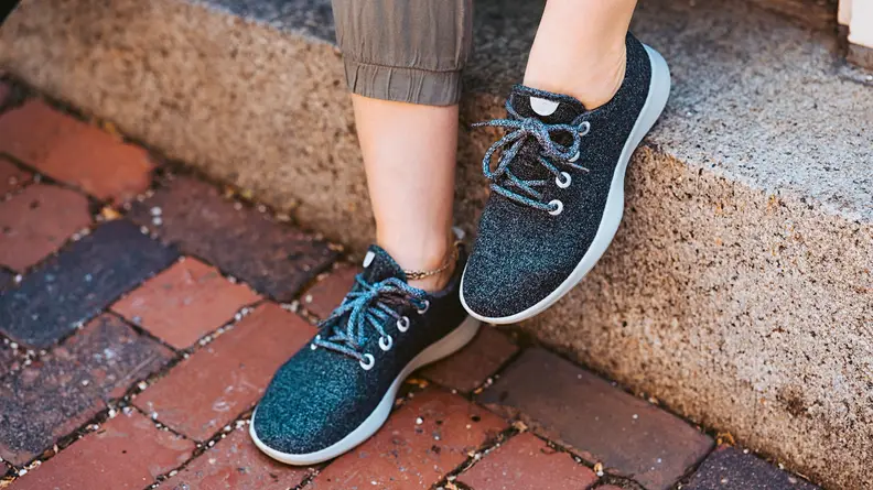Person wear Allbirds sneakers, standing on brick