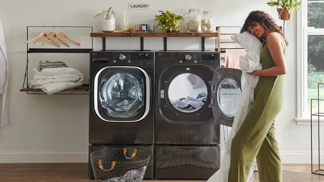 A person unloads a dryer full of laundry.