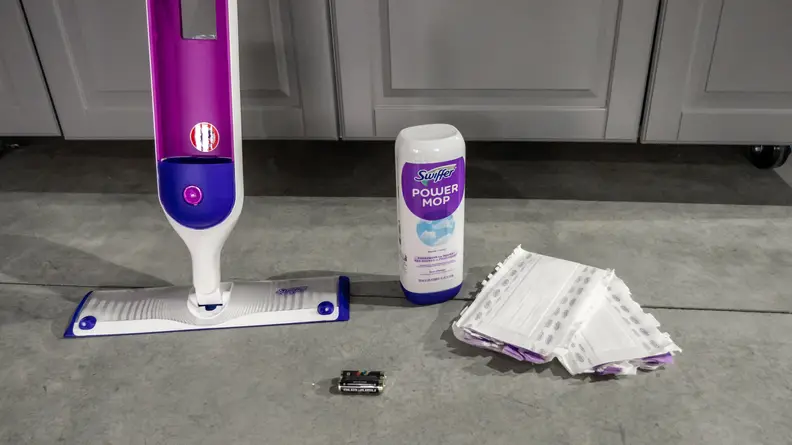 A Swiffer Powermop system is positioned next to a bottle of cleaner, mop pads, and parts during testing for the best mop.