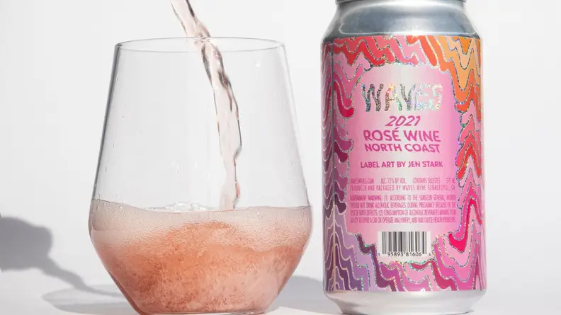 Can of Waves rosé next to wine being poured inside of stemless wine glass.