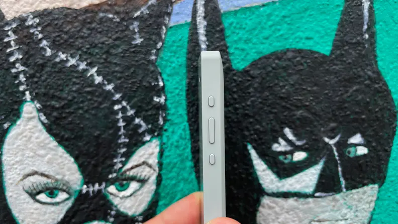 Person holding up small smartphone in front of painted wall.