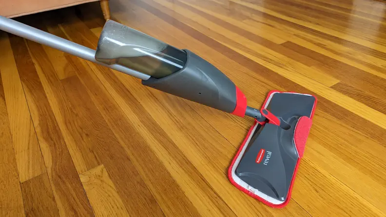 A gray and red Rubbermaid mop with microfiber pad pushes across a hardwood floor during testing for the best mops.
