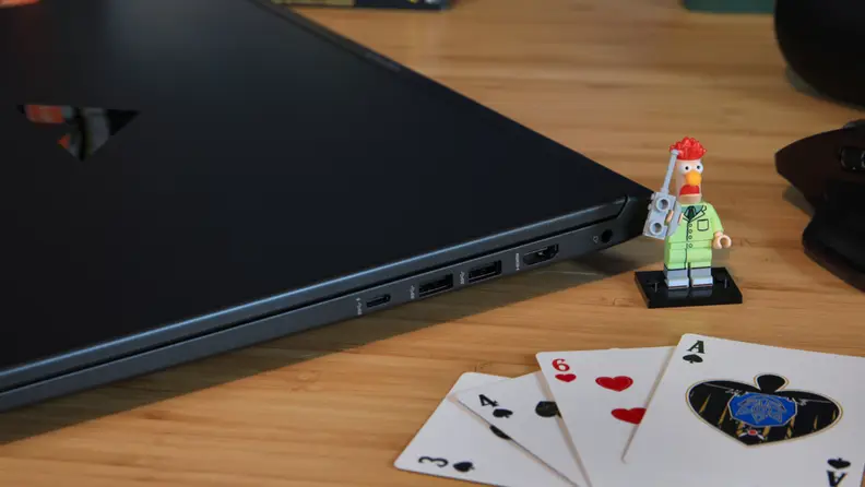 The side of the HP Victus 16 next to a Lego mini figure and some playing cards, showing off the connectivity ports.