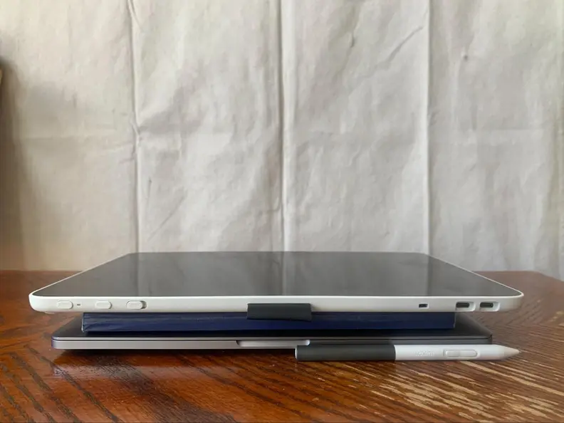 The Wacom drawing tablet sits on top of a sketchbook and laptop—the digital pen sits next to it.