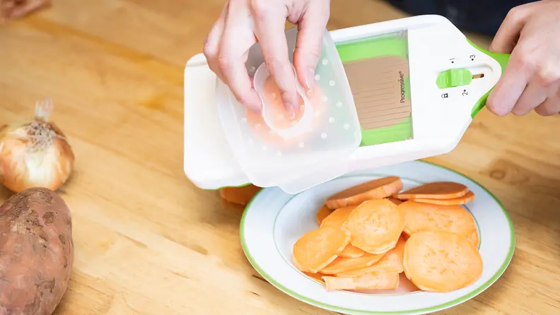 A sweet potato is sliced using the Prepworks by Progressive Adjust-a-Slice Mandoline