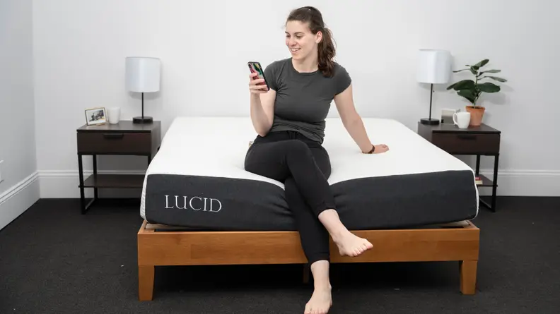 A person sitting on the bottom edge of the Lucid mattress.
