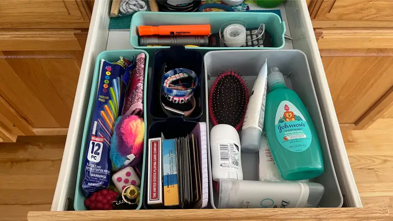 An organized junk drawer pulled open with flashlights, pens, and other small household objects