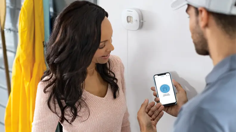 Person smiling while other person shows display on phone screen.