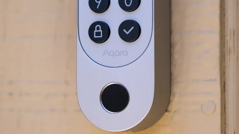 An upclose shot of the silver Aqara U200 smart lock keypad hanging on a light brown door