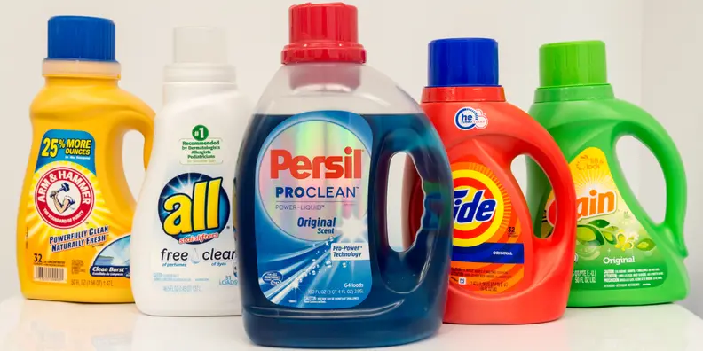 Laundry detergents like Arm and Hammer, All, Persil, Tide, and Gain lined up next to each other.