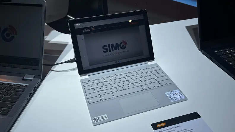 The Asus Chromebook CM30 open on a white table between other laptops.