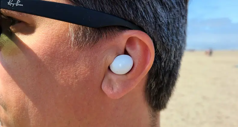 Samsung Galaxy Buds 2 is shown in the ear against a sunny beach.