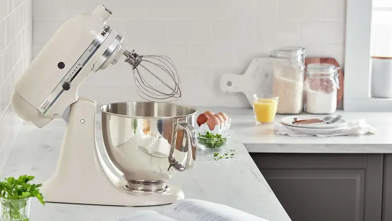 A beige stand mixer on a kitchen counter with its head tilted