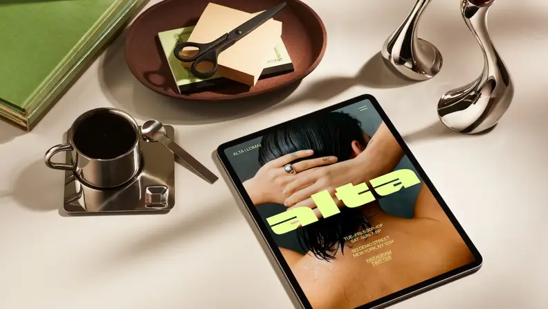 A tablet on a desk displays a bold website design created with Squarespace templates beside coffee, books, and stationery.