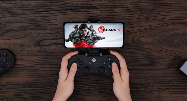 Hands grip a gaming controller with a phone attached