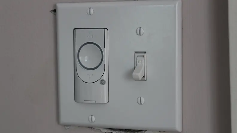 A white smart ceiling fan switch on a wall.