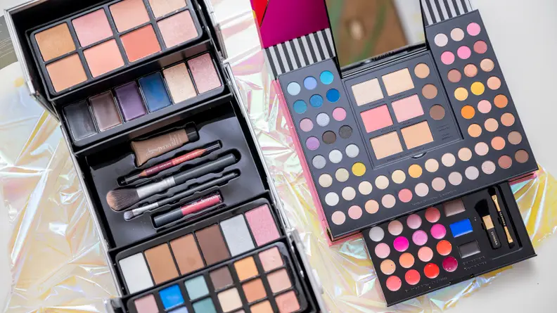 Two makeup kits sitting side by side open to reveal makeup.