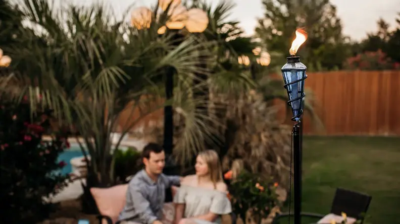 A blue glass torch lit outside, with a couple smiling in the background