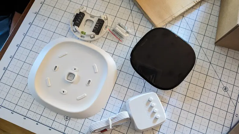 A disassembled Ecobee Smart Thermostat Enhanced sits on a ruler board.