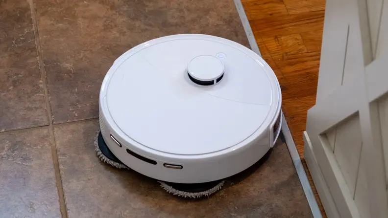 A round robot vacuum on a tile floor