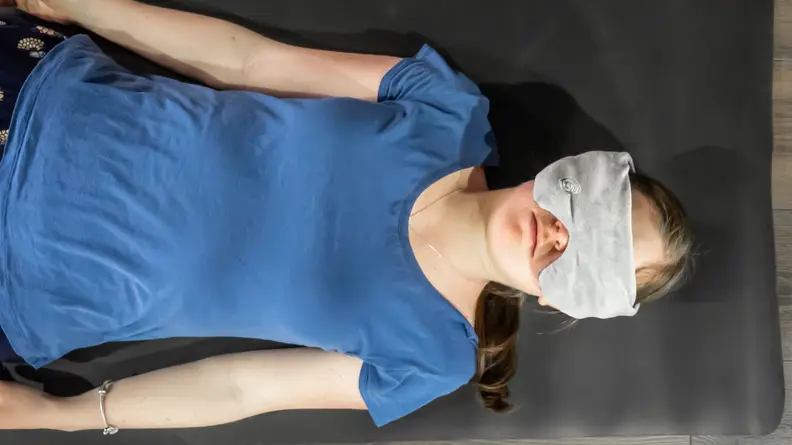 Person laying on mattress with weighted eye mask on over face.