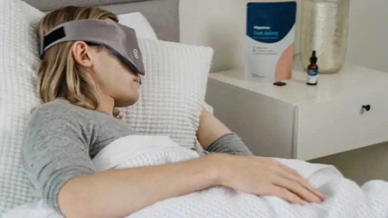 a woman sleeps in bed wearing a Gravity Weighted Mask