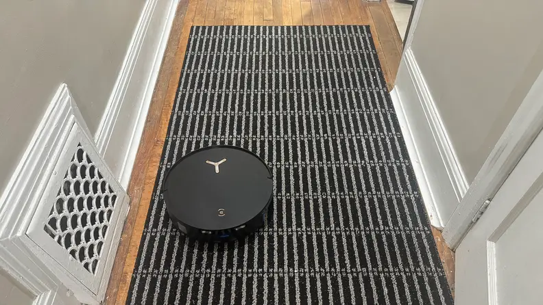 A black robot vacuum in a hallway