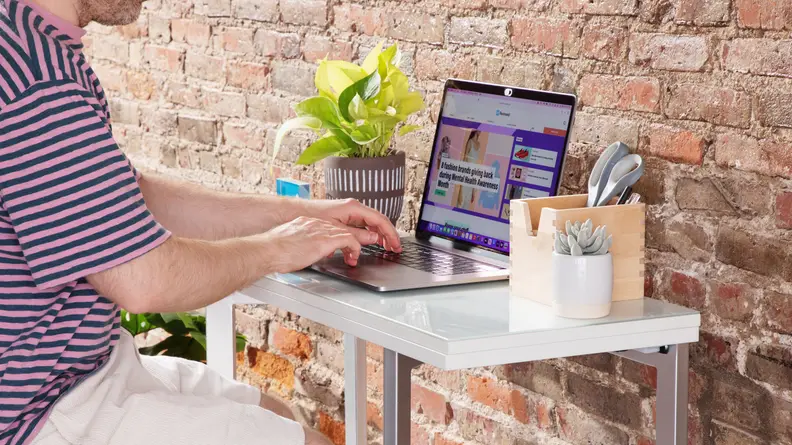 A small desk in workstation mode with a person sitting at the desk and typing on a computer