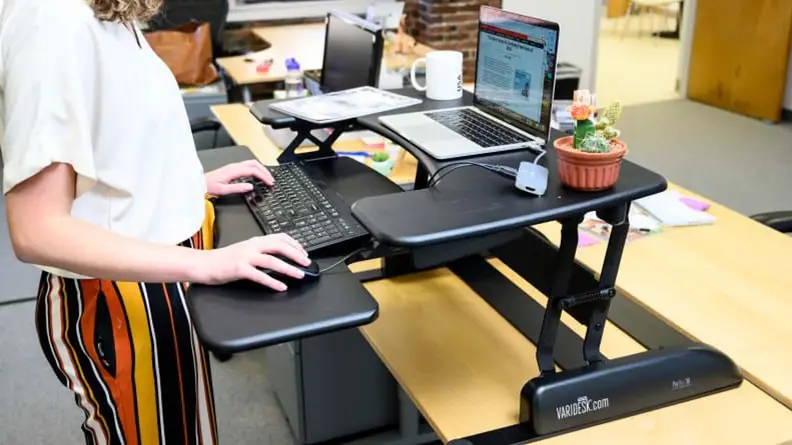 Close-up of a person working on a laptop at the VariDesk Pro Plus standing desk.