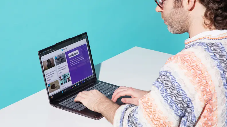 A person typing on the Lenovo Slim 7 at a white desk.
