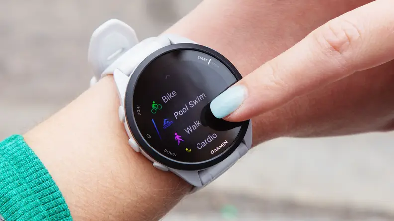 A woman wearing the Garmin Forerunner 165 watch and tapping the screen.